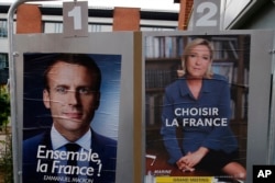 FILE - Election campaign posters for French centrist presidential candidate Emmanuel Macron and far-right candidate Marine Le Pen are posted in front of the polling station where Marine Le Pen will vote in Henin Beaumont, northern France, May 6, 2017.