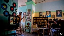 រូបឯកសារ៖ បុរស​ម្នាក់​មើល​ការ​ស្បថ​ចូល​កាន់​តំណែង​របស់​លោក ដូណាល់ ត្រាំ តាម​កញ្ចក់​ទូរទស្សន៍​ នៅ​ពេល​លោក​អង្គុយ​នៅជិត​រូប​ថត​លោក Raul Castro ប្រធានាធិបតី​គុយបា។