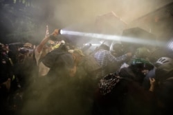 Demonstrators push on a fence as tear gas is deployed during a Black Lives Matter protest at the Mark O. Hatfield United States Courthouse, July 25, 2020, in Portland, Ore.