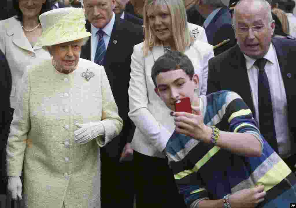 Seorang remaja mengambil gambar selfie di depan Ratu Elizabeth II yang berkunjung ke Belfast, Irlandia utara.