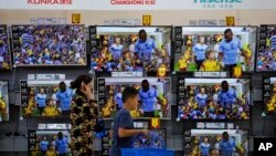 A woman and a child pass Chinese brands of flat screen TVs on display at a hypermarket in Beijing, July 11, 2018. 