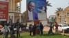 People stand under the poster of Central Africa Republic's President Francois Bozize in Bangui on December 28, 2012