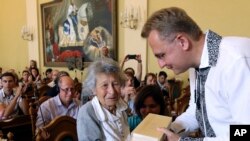 Lviv Mayor Andriy Sadoviy, right, presents a glass copy of an old metal synagogue key to Yanina Hescheles, Polish writer and a Nazi concentration camp survivor, at a ceremony commemorating the 75th anniversary of the annihilation of the city's Jewish population by Nazi Germany in Lviv, Ukraine, Sunday, Sept. 2, 2018. 