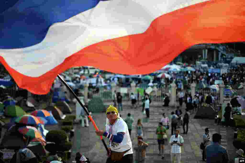 Seorang pengunjuk rasa anti-pemerintah di Thailand melambaikan bendera nasional Thailand dalam&nbsp; unjuk rasa yang berkelanjutan di lokasi demonstrasi di Victory Monument di pusat kota Bangkok.&nbsp; Keputusan pengadilan untuk mengembalikan kepada pemerintah dan komisi pemilihan untuk memutuskan apakah pemilu akan ditunda atau tidak karena adanya kerusuhan yang mematikan, menyebabkan pemilihan yang kontroversial itu berada dalam ketidakpastian. 