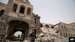 FILE - Shi'ite rebels, known as Houthis, stand guard in front of Yemen's Defense Ministry building in Sanaa, Yemen on June 10, 2015, after it was damaged by Saudi-led airstrikes. 