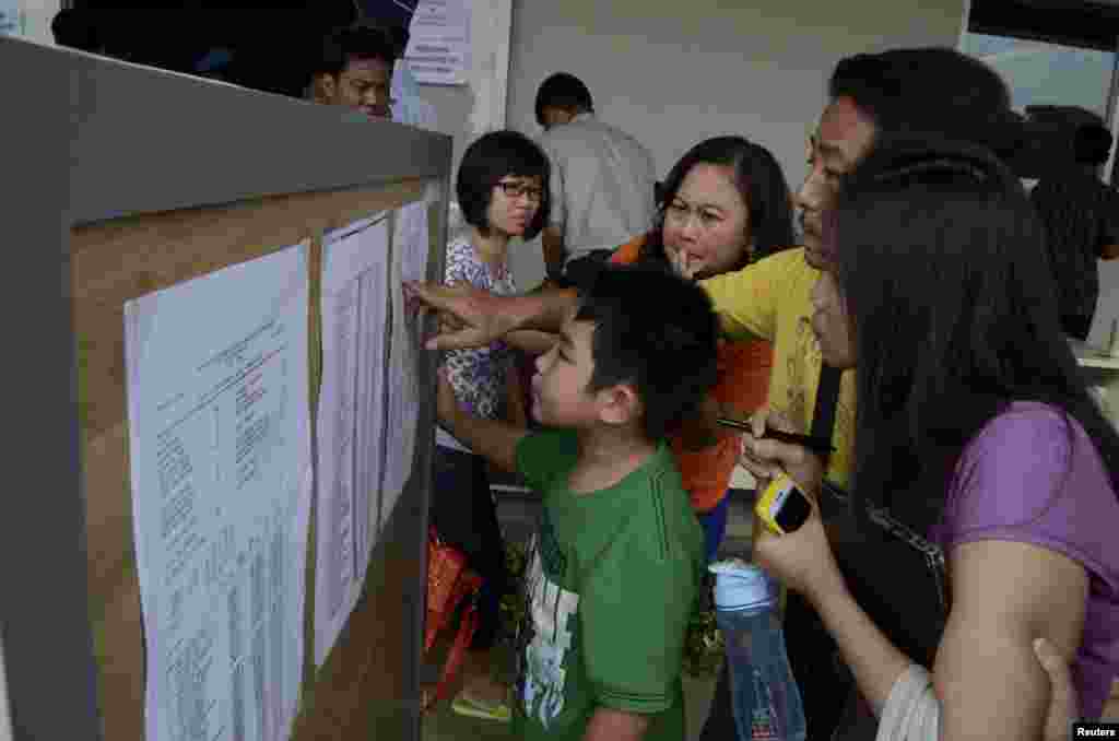 Family members of passengers on board AirAsia flight QZ 8501 look at a passenger list inside a crisis center at Juanda Airport in Surabaya, East Java, Dec. 28, 2014, in this photo taken by Antara Foto.