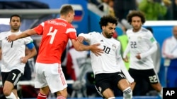 Pesepak bola Rusia, Sergei Ignashevich (kiri), dan Mohamed Salah dari Mesir (kanan) berebut menguasai bola dalam laga penyisihan Grup A antara Rusia dan Mesir di Piala Dunia 2018 di Stadion St. Petersburg, Rusia, 19 Juni 2018.