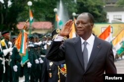 FILE - Ivory Coast's President Alassane Ouattara salutes during a parade to commemorate the country's 54th Independence Day, outside the presidential palace in Abidjan, August 7, 2014.