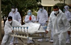 Relatives react as healthcare workers pull a stretcher carrying the body of a person who died from COVID-19, at a mortuary in Ahmedabad, India, May 8, 2021.
