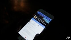 In this March 1, 2016 photo, a man views Cambodian Prime Minister Hun Sen's Facebook page on his mobile phone at a side walk in downtown Phnom Penh, Cambodia.