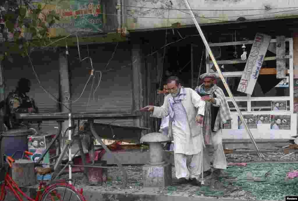 Afghan residents leave the site of a suicide car bomb attack in Jalalabad province, Afghanistan, March 20, 2014. 