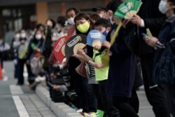 Local people wait for torchbearers to arrive at the torch relay route of the first section of the Fukushima Torch Relay in Naraha, Fukushima prefecture, northeastern Japan, March 25, 2021.