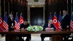 President Donald Trump and North Korean leader Kim Jong Un participate in a signing ceremony during a meeting on Sentosa Island, June 12, 2018, in Singapore.