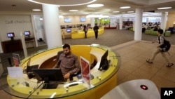 FILE - Northeastern University graduate student Shabbir Hussain, of Indore, India, left, views a computer screen at the entrance to the Snell Library on the Northeastern University campus in Boston, May 24, 2016. 