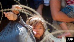 Para migran menunggu polisi Makedonia mengijinkan mereka menyeberang Makedonia melalui perbatasan antara Yunani dan Makedonia dekat kota Gevgelija pada 28 Agustus 2015.