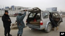 Afghan policemen search a car at a check point in Kabul, February 26, 2012.