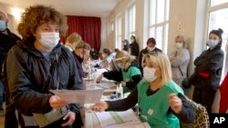A woman is handed her ballot at a polling station during the national municipal elections in Tbilisi, Georgia, Oct. 2, 2021.