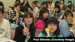 Students at a university in Japan use interactive response paddles during an activity.