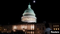 Seseorang duduk di luar Capitol AS setelah Ketua DPR AS Kevin McCarthy mencapai kesepakatan tentatif dengan Presiden Joe Biden untuk menaikkan plafon utang AS. di Washington, AS, 27 Mei 2023. ( Foto: REUTERS/Nathan Howard)