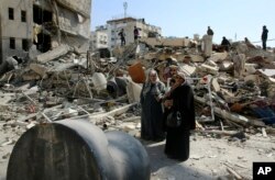 Palestinians search for their family's belongings amid the rubble of destroyed building near a Hamas security building that was destroyed in an Israeli airstrike late Monday, in Gaza City, March 27, 2019.