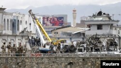 Petugas keamanan Afghanistan memeriksa lokasi ledakan bom di Kabul, Afghanistan (19/4). 