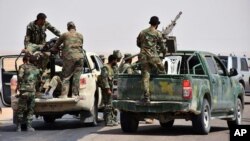 FILE - This photo released Sept 4, 2017, by the Syrian official news agency SANA shows Syrian troops and pro-government gunmen standing on pickup trucks with heavy machine guns mounted on them, in the eastern city of Deir el-Zour, Syria.