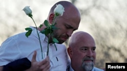 Will Beck, a survivor of the attack at Columbine high school, hugs Lee Andres (R) at the Columbine memorial a day before the school shooting's 20th anniversary, in Littleton, Colorado, April 19, 2019. 