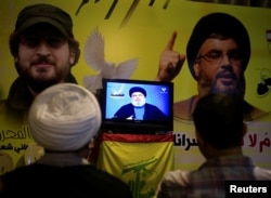 FILE - A Shiite sheikh watches Lebanon's Hezbollah leader Sayyed Hassan Nasrallah speaking on television in Nabatieh in southern Lebanon, Aug. 4, 2017.