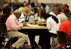 FILE - Job seekers take advantage of banks of tables to fill out their job applications at the Mississippi Employment Expo in Jackson, Miss., March 17, 2009.