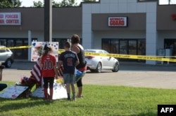 Zach, Zoe and Melissa Cates add to a makeshift memorial near the scene of a shooting at a Armed Forces Career Center/National Guard recruitment office in Chattanooga, Tennessee, July 16, 2015.