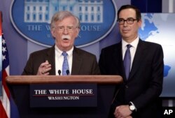 National security adviser John Bolton speaks as Treasury Secretary Steven Mnuchin listens during a press briefing at the White House, Jan. 28, 2019, in Washington.