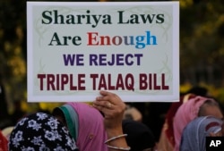 In this Jan. 7, 2018 file photo, an Indian Muslim woman holds a placard during a protest against a new draft law aimed at banning "Triple Talaq," a Muslim practice of instant divorce, in Ahmadabad, India. India's government on Wednesday, Sept. 19, approve