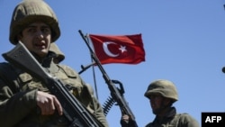 Prajurit AD Turki berjaga-jaga saat warga Kurdi menunggu dan berharap dapat memasuki kota Cizre, sebuah kota yang dikenakan jam malam sebagai bagian dari operasi melawan pemberontak Kurdi yang kontroversial, tanggal 22 Maret 2016 di Mardin untuk perayaan Newroz (foto: ILYAS AKENGIN/AFP/Getty Images)