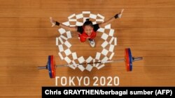 Atlet Indonesia Windy Cantika Aisah saat berlaga di cabang olahraga angkat besi 49 kg putri di Olimpiade Tokyo 2020, 24 Juli 2021. (Foto: Chris GRAYTHEN/berbagai sumber/AFP)