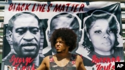 Actor Steven Thompson poses for a picture next to a poster of George Floyd in Los Angeles, April 2, 2021. Thompson is choosing not to watch the televised trial of Derek Chauvin.