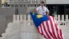 FILE - A worker rolls up a Malaysian national flag after the arrival of the Malaysian delegation at Beijing's International Airport ahead of a Belt and Road forum in Beijing, China, May 12, 2017.