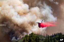 FILE - An air tanker drops retardant while trying to stop the Oak Fire from progressing in Mariposa County, California, on July 24, 2022.