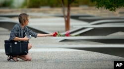 Seorang perempuan menyentuh bunga di bangku di Memorial Pentagon. (Foto: Dok)