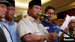 Kandidat presiden Indonesia, Prabowo Subianto memberikan pidato untuk menyatakan kemenangan pemilu saat pasangannya Sandiaga Uno berdiri di sebelahnya di Jakarta, Indonesia, 18 April 2019.