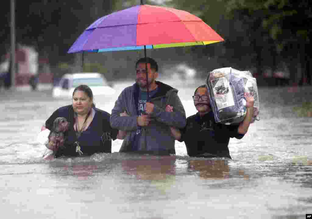 Felix Yanez, au centre, aide Lucy Olvio et Judy à marcher dans l&#39;eau lors des inondations à Houston, Texas, 18 avril 2016.