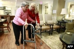 Alexis McKenzie, right, executive director of an Alzheimer's assisted-living home in Washington, walks with resident Catherine Peake in February