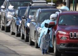 Health care workers test people at a drive-thru testing station run by the state health department, for people who suspect they have novel coronavirus, in Denver, Colorado, March 11, 2020.