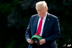 FILE - President Donald Trump holds hats reading "Make Our Farmers Great Again!" as he walks across the South Lawn before boarding Marine One at the White House in Washington, Aug. 30, 2018, before heading to a rally in Evansville, Indiana.