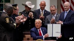 ក្រុម​មន្ត្រី​ប៉ូលិស​បាន​នាំ​គ្នា​ទះដៃ បន្ទាប់ពី​ប្រធានាធិបតី​សហរដ្ឋអាមេរិក លោក ដូណាល់ ត្រាំ បាន​ចុះ​ហត្ថលេខា​លើ​បទបញ្ជា​មួយ​ស្ដី​ពី​កំណែទម្រង់​ប៉ូលិស នៅ​ឧទ្យាន Rose Garden ក្នុង​សេតវិមាន កាល​ពី​ថ្ងៃ​អង្គារ ទី​១៦ ខែមិថុនា ឆ្នាំ​២០២០។ (AP Photo/Evan Vucci)