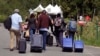 A family from Haiti approaches a tent in Saint-Bernard-de-Lacolle, Quebec, stationed by Royal Canadian Mounted Police, as they haul their luggage down Roxham Road in Champlain, N.Y., Aug. 7, 2017.