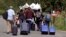 A family from Haiti approaches a tent in Saint-Bernard-de-Lacolle, Quebec, stationed by Royal Canadian Mounted Police, as they haul their luggage down Roxham Road in Champlain, N.Y., Aug. 7, 2017.