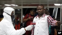 In this Aug. 6, 2014 photo, a Nigerian port health official uses a thermometer on a worker at the arrivals hall of Murtala Muhammed International Airport in Lagos, Nigeria. 
