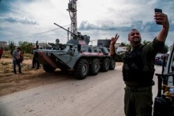 A Syrian security forces member takes a selfie by a Russian military vehicle during a patrol near the Syria-Turkey border, in northern Syria, Oct. 25, 2019.