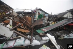 FILE - A man clears debris from the remains of his home that was damaged by waves from Typhoon Hagupit in Legazpi, Philippines, Dec. 8, 2014.
