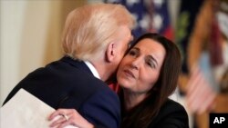 صدر ٹرمپ دستخظوں کے بعد رائلی کی والدہ کو گلے لگا رہے ہیں۔ اے پی